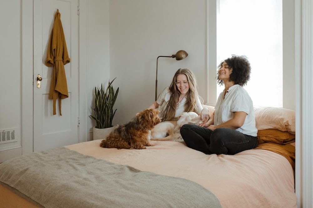 Two girls with a puppy on a bed.